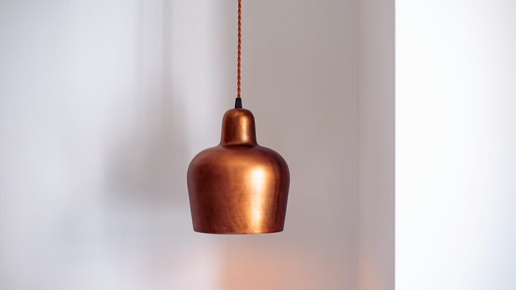 Hanglamp van koper in een minimalistisch interieur, die warm licht en sfeer toevoegt – perfect voor koper in interieur.
