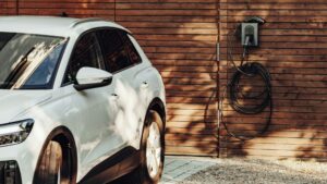 Witte SUV geparkeerd bij houten wand met geïntegreerd laadpunt voor een luxe oprit met laadpunt