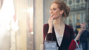 Vrouw geniet zichtbaar van luxe verkoopervaring met meerdere designer shopbags in haar hand.