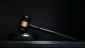 Houten rechtershamer op donkere achtergrond, symbool voor oplossing bij juridisch probleem.