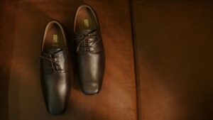 Bruin leren paar verzorgde schoenen op een leren bank, passend bij een verzorgde uitstraling.